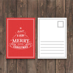 CUSTOM PRINTED HOLIDAY POSTCARD FEATURING A RED CHRISTMAS DESIGN WITH A TRADITIONAL MAILING LAYOUT DISPLAYED ON A WOODEN BACKGROUND.