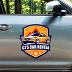 CUSTOM SHIELD-SHAPED MAGNETIC VEHICLE SIGN FEATURING CJ’S CAR RENTAL BRANDING WITH ORANGE AND NAVY GRAPHICS, APPLIED TO THE SIDE DOOR OF A SILVER CAR.