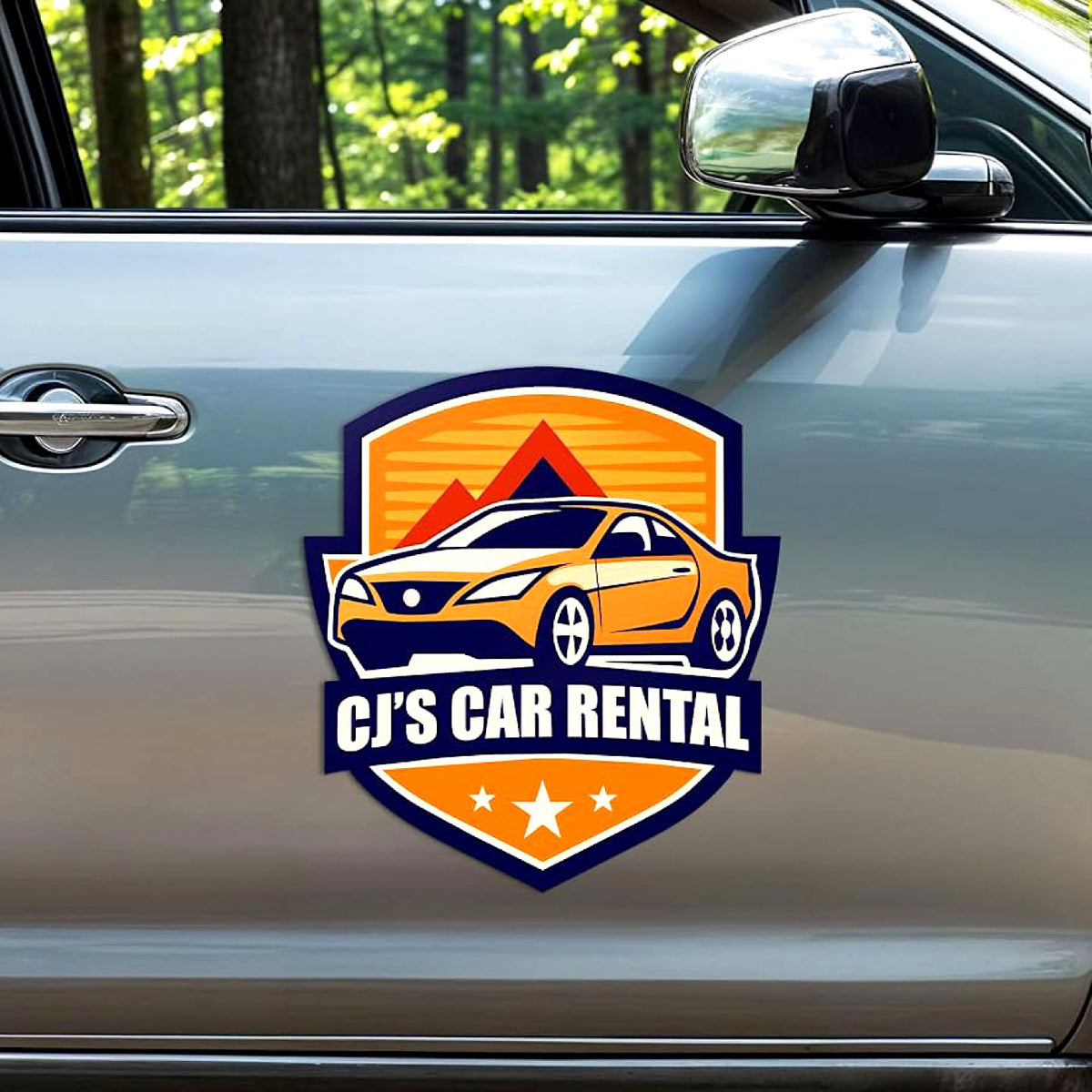 CUSTOM SHIELD-SHAPED MAGNETIC VEHICLE SIGN FEATURING CJ’S CAR RENTAL BRANDING WITH ORANGE AND NAVY GRAPHICS, APPLIED TO THE SIDE DOOR OF A SILVER CAR.