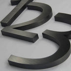 MATTE BLACK 3D METAL NUMBERS FEATURING “2” AND “3” WITH A BRUSHED FINISH, DISPLAYED ON A LIGHT GRAY BACKGROUND.