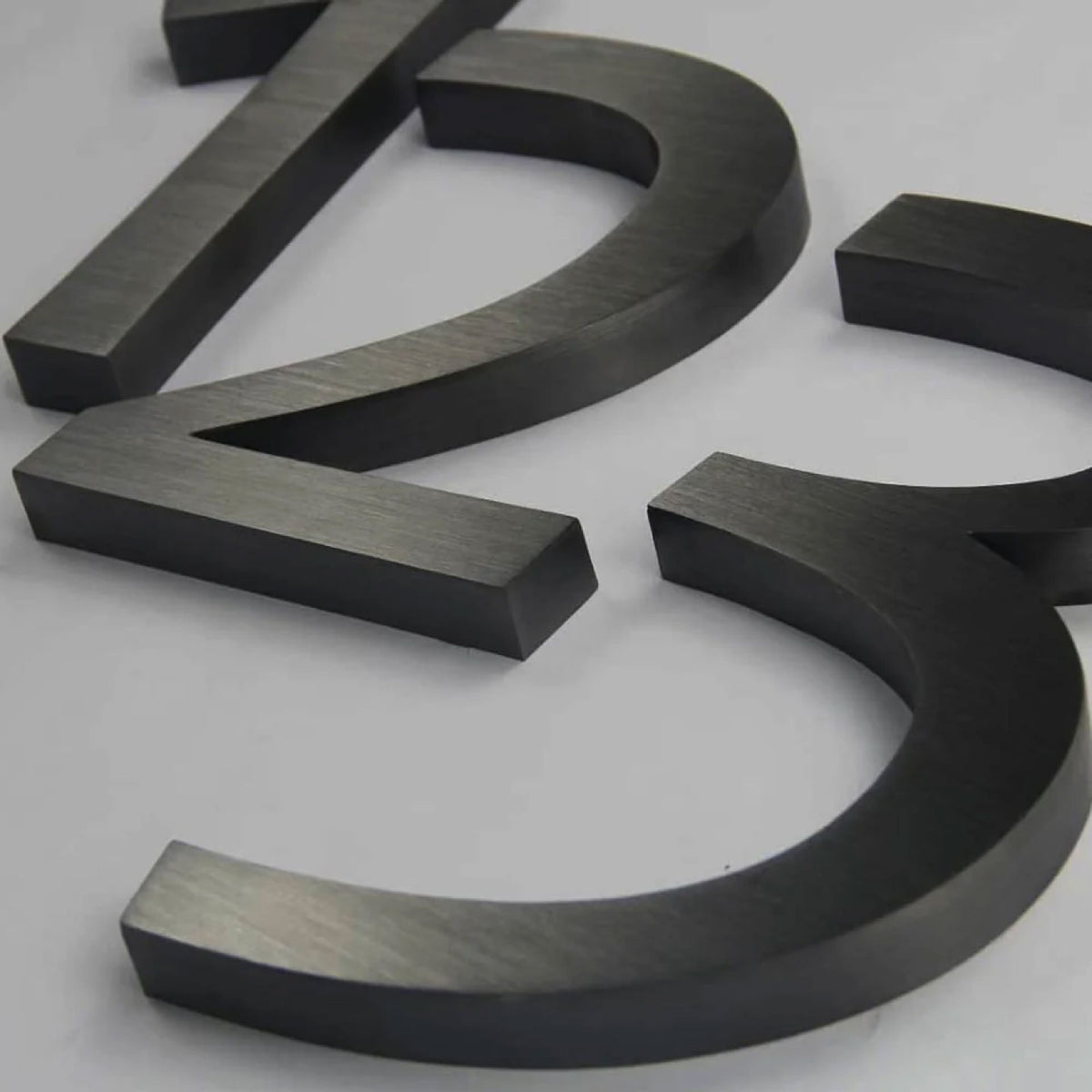 MATTE BLACK 3D METAL NUMBERS FEATURING “2” AND “3” WITH A BRUSHED FINISH, DISPLAYED ON A LIGHT GRAY BACKGROUND.