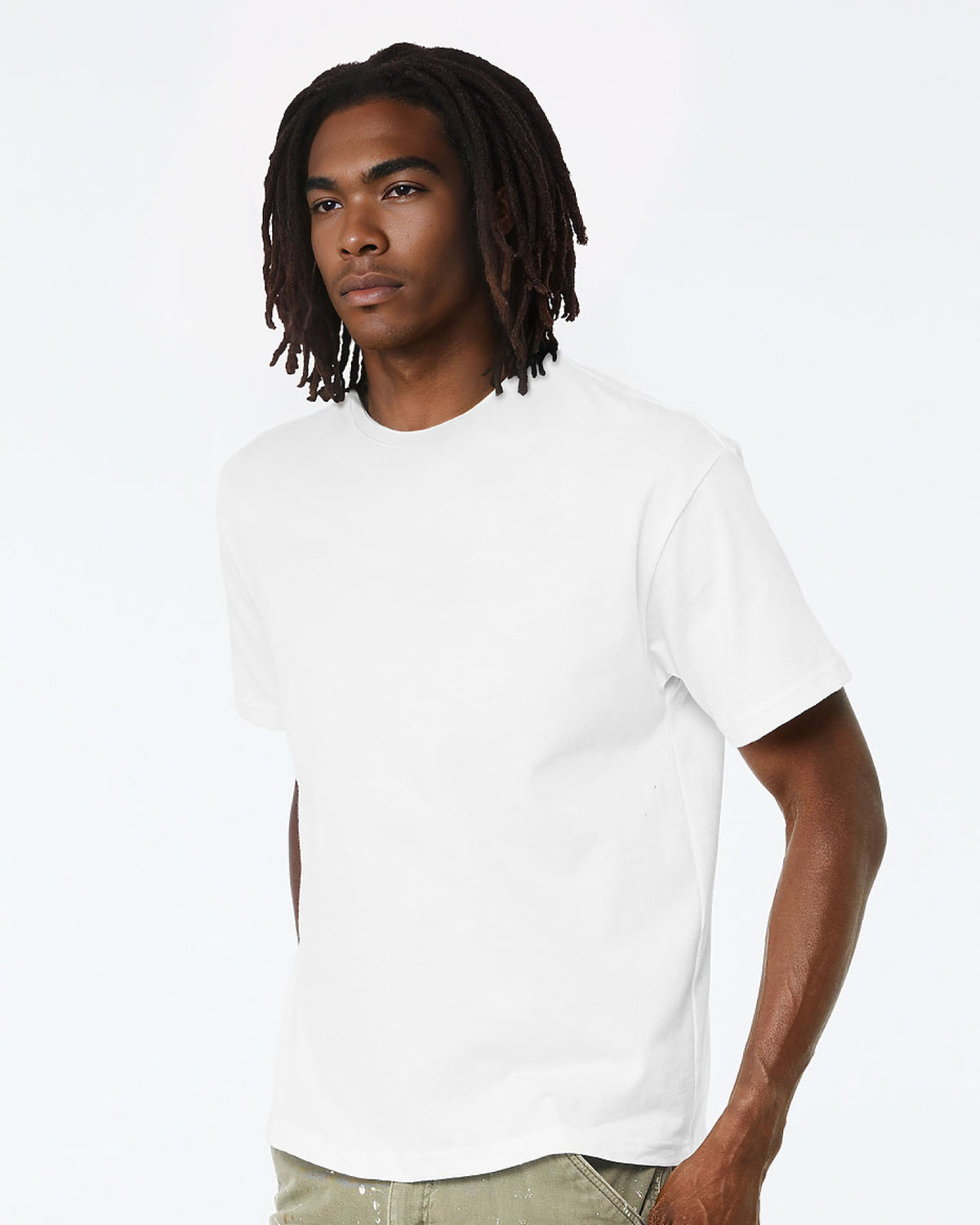 A man with dark dreadlocks wearing a plain white short-sleeve crewneck t-shirt, photographed against a clean white studio background.