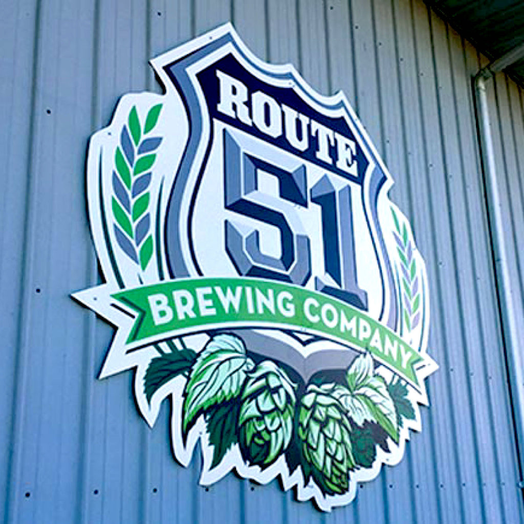 CUSTOM PRINTED ALUMINUM SIGN FEATURING ROUTE 51 BREWING COMPANY BRANDING WITH A SHIELD, WHEAT, HOPS, AND GREEN BANNER GRAPHICS, MOUNTED ON A BLUE CORRUGATED METAL EXTERIOR WALL.