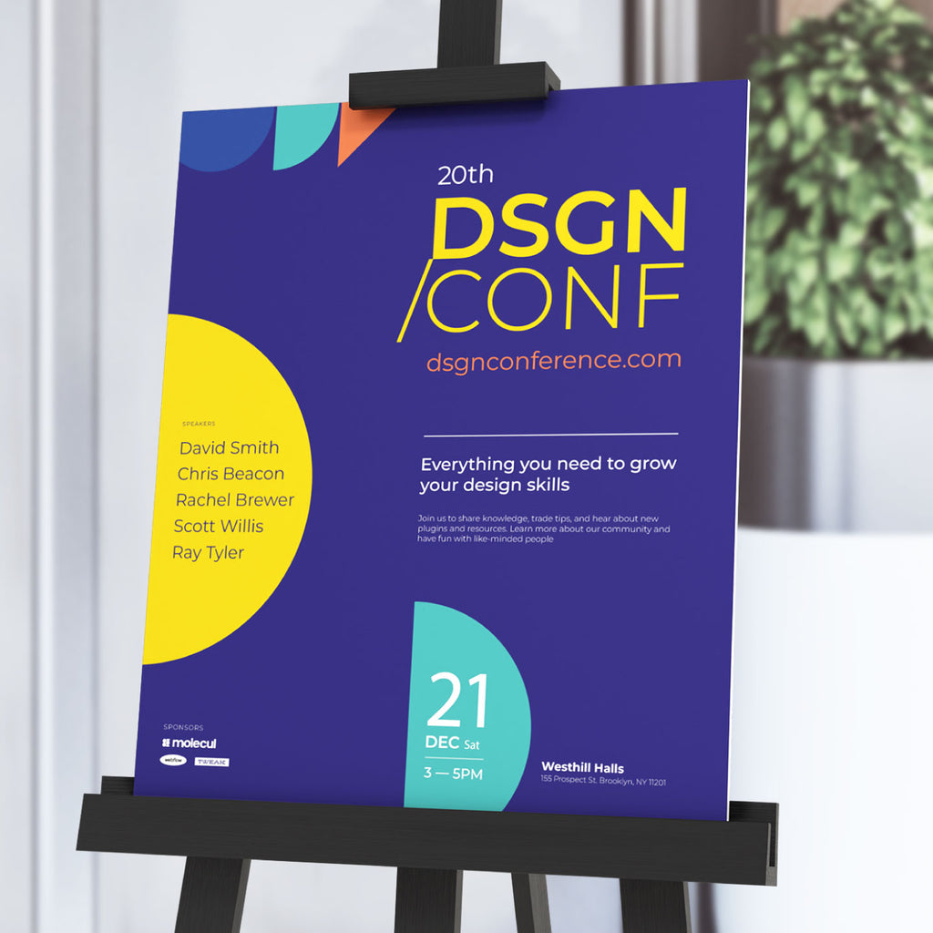 CUSTOM PRINTED FOAM BOARD POSTER FEATURING DSGN / CONF CONFERENCE GRAPHICS, DISPLAYED ON A BLACK EASEL STAND IN A MODERN INDOOR EVENT SETTING.