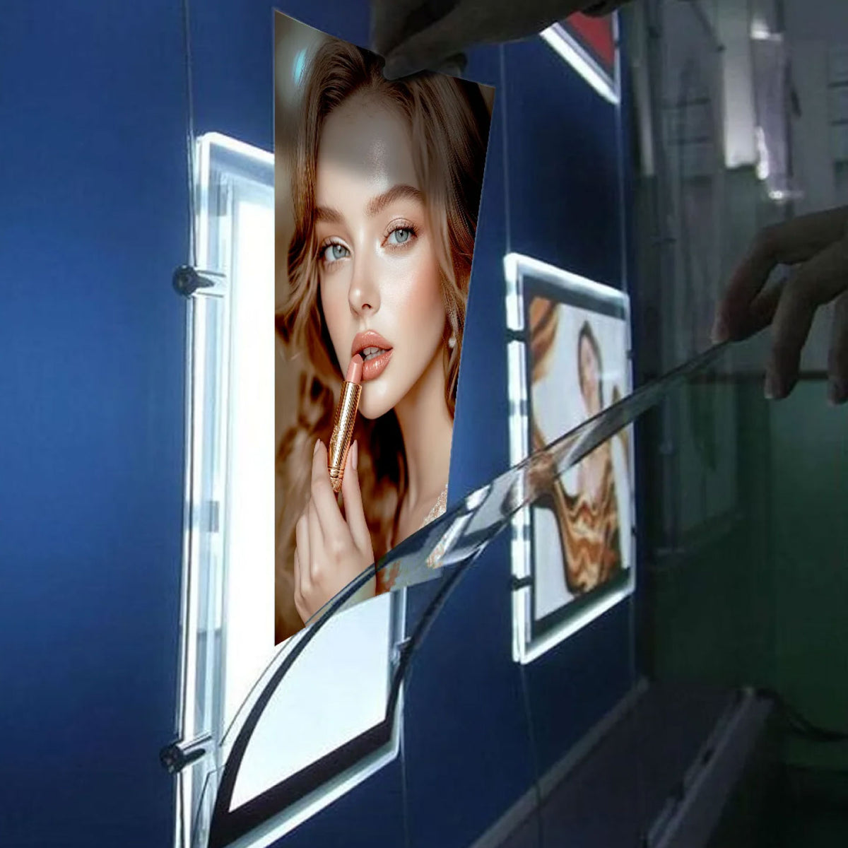 CUSTOM PRINTED TRANSLUCENT BACKLIT SIGN INSERT FEATURING A BEAUTY PORTRAIT OF A WOMAN APPLYING LIPSTICK, ILLUMINATED IN A VERTICAL LED LIGHT TRANSLUCENT ACRYLIC SURFACES MOUNTED ON A DARK BLUE WALL.