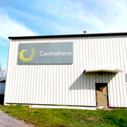 CUSTOM PRINTED ACM BUILDING SIGN FEATURING CENTROTHERM BRANDING WITH A GRAY BACKGROUND AND YELLOW LOGO, MOUNTED ON THE EXTERIOR OF A WHITE INDUSTRIAL BUILDING.